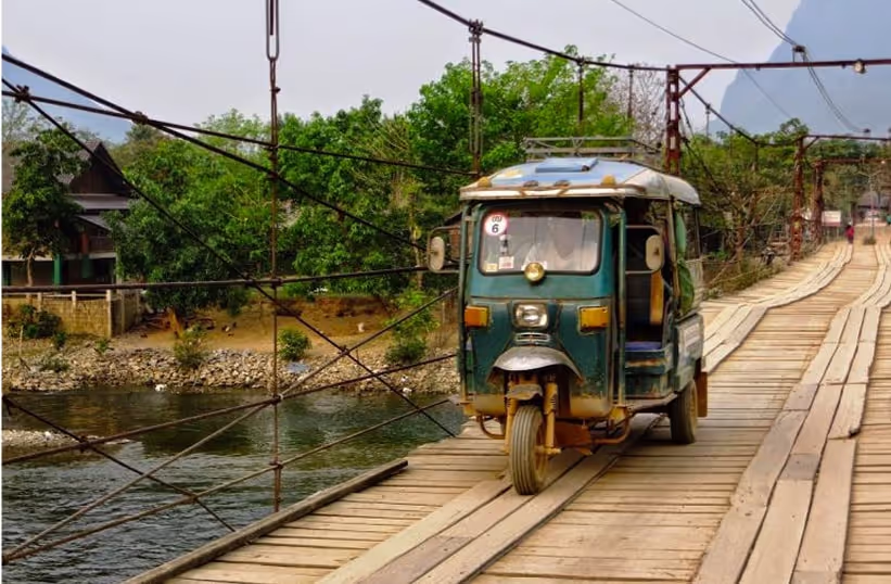 A tuk tuk crossing a bridge in Vang Vieng
